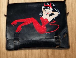 Cartoon Pin-Up auf Leder-Schul-Tasche mit silber Punkten auf dem Catsuit.